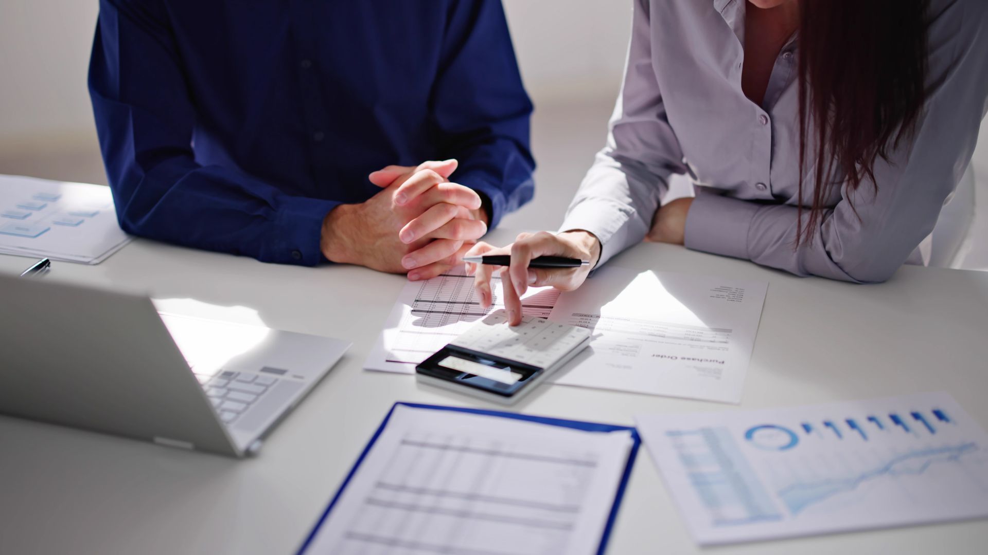 Two people reviewing printed charts and a tablet at a table